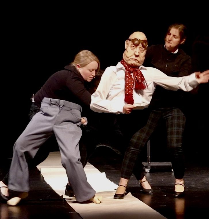 Deux interprètes manipulent la marionnette du vieux philosophe au foulard rouge